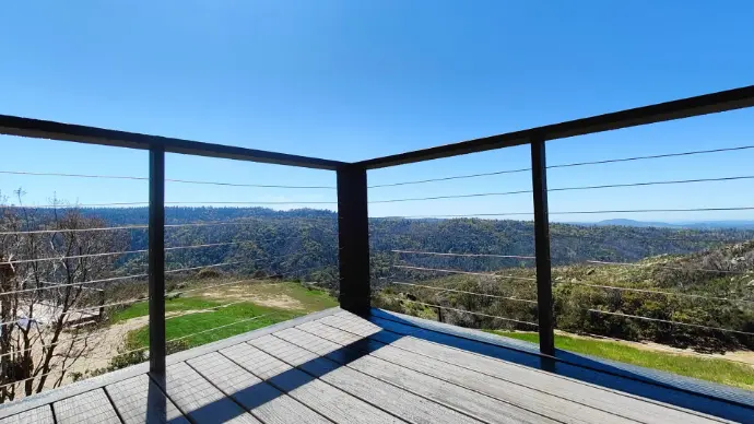 Camino hillside deck with slim cable railing and cool-gray composite boards for unobstructed vistas. Engineered posts and footings handle wind and seasonal movement—low-maintenance, high-impact outdoor space.