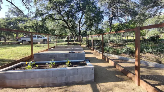 Welded-wire perimeter fence, compacted DG paths, and leveled block planters create a clean, productive garden. Apex Exteriors landscaping in El Dorado Hills focuses on drainage, access, and long-term durability.