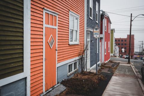 Exterior image taken from sidewalk of multiple colored buildings